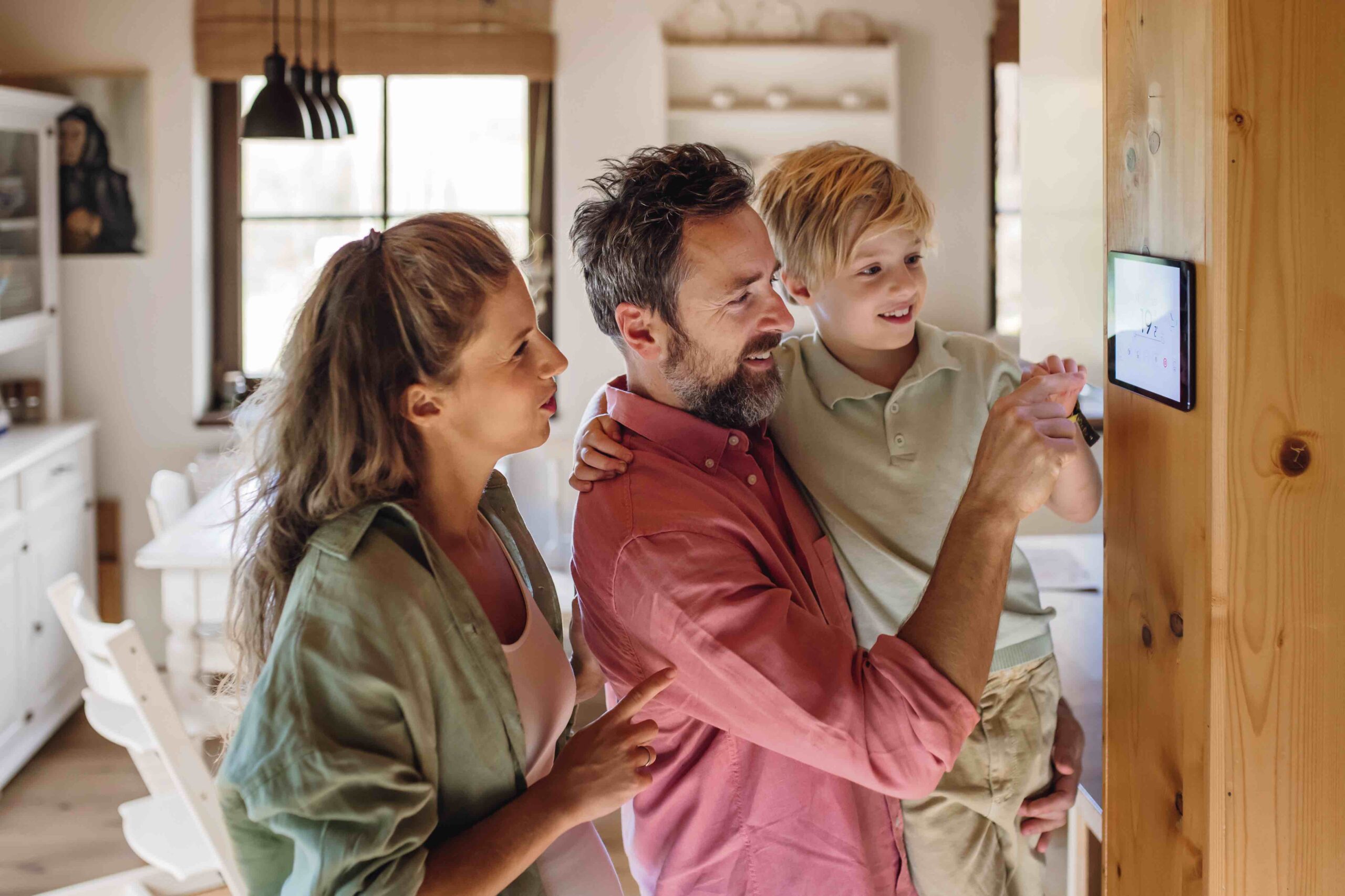 Family looking at smart thermostat, adjusting, lowering heating temperature at home. Concept of sustainable, efficient, and smart technology in home heating and thermostats. Retrofit Design ltd